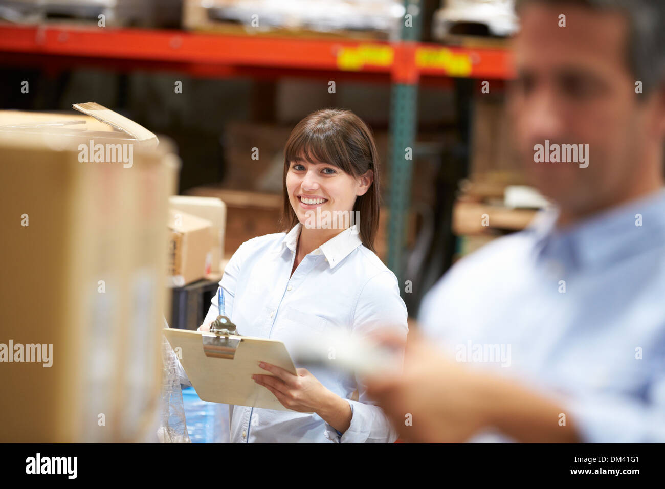 Manager en almacén con cuadro de análisis de trabajador en primer plano Foto de stock
