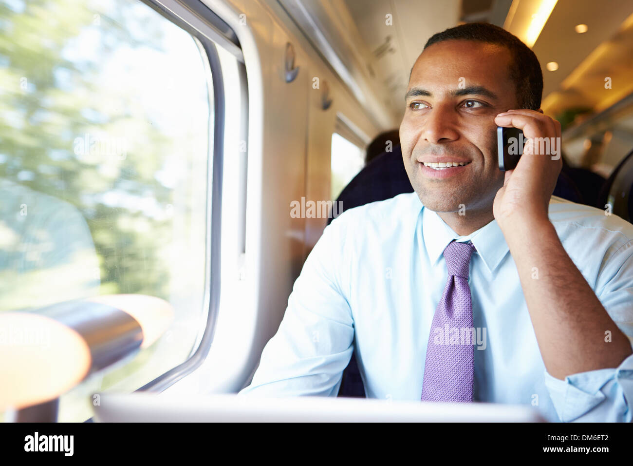 El empresario van a trabajar en el tren a través de teléfono móvil Foto de stock