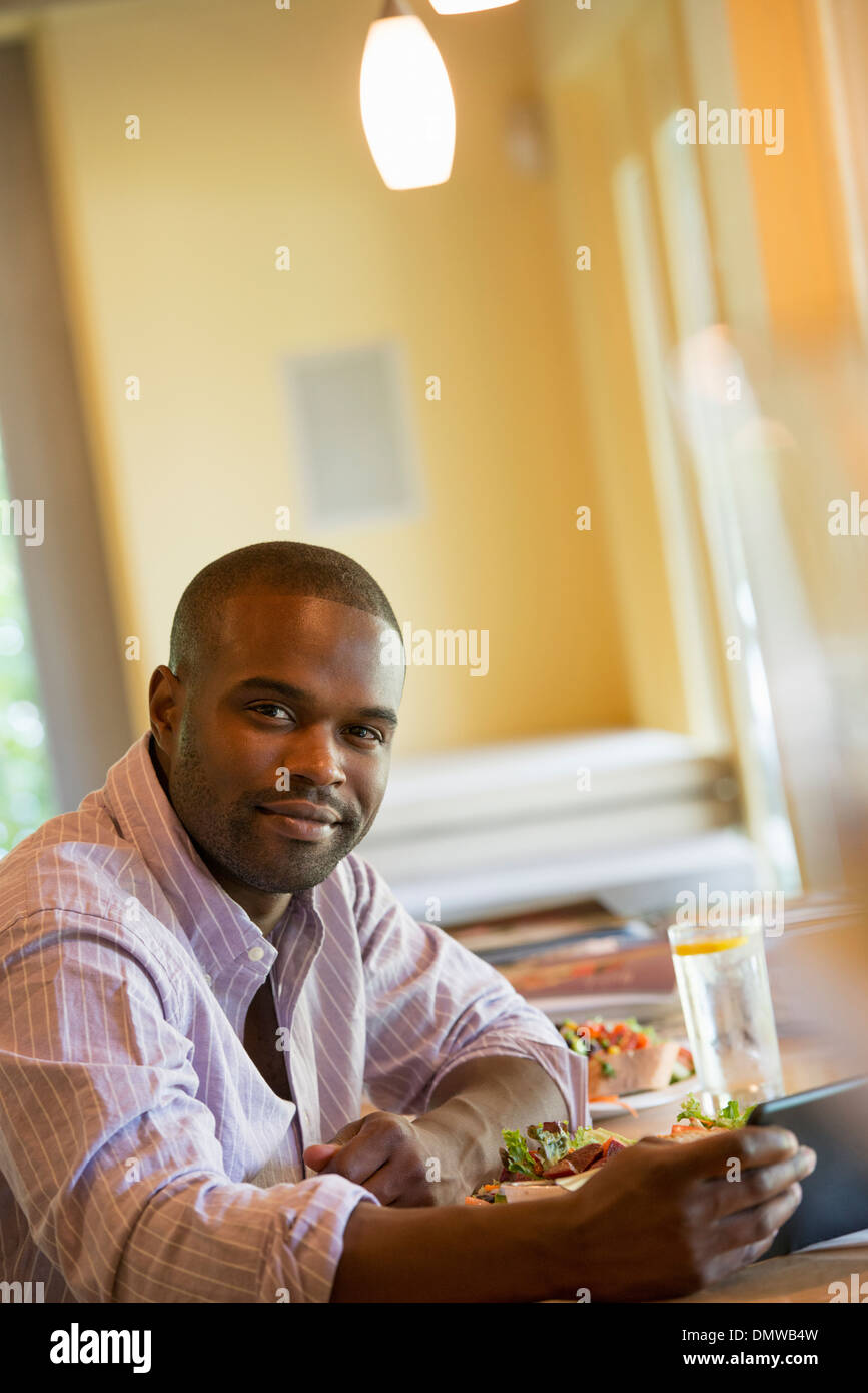 Un hombre en una cafetería con una tableta digital. Foto de stock