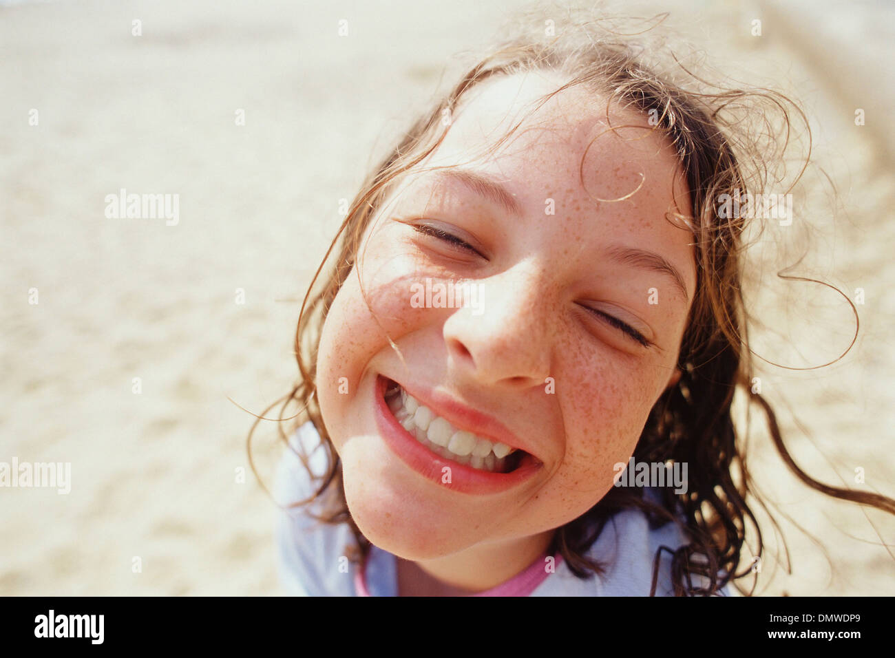 Una joven con una amplia sonrisa los ojos cerrados y el cabello húmedo fuera en la lluvia. Foto de stock