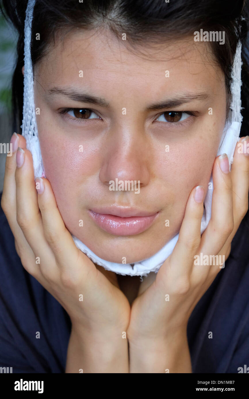 Adolescente recuperando de la extracción de los dientes de la sabiduría usando una compresa fría Foto de stock