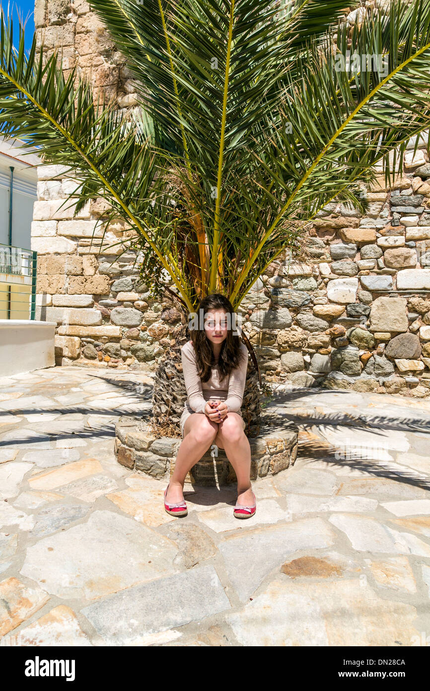 Triste chica sentada en la parte inferior de una palmera Fotografía de  stock - Alamy