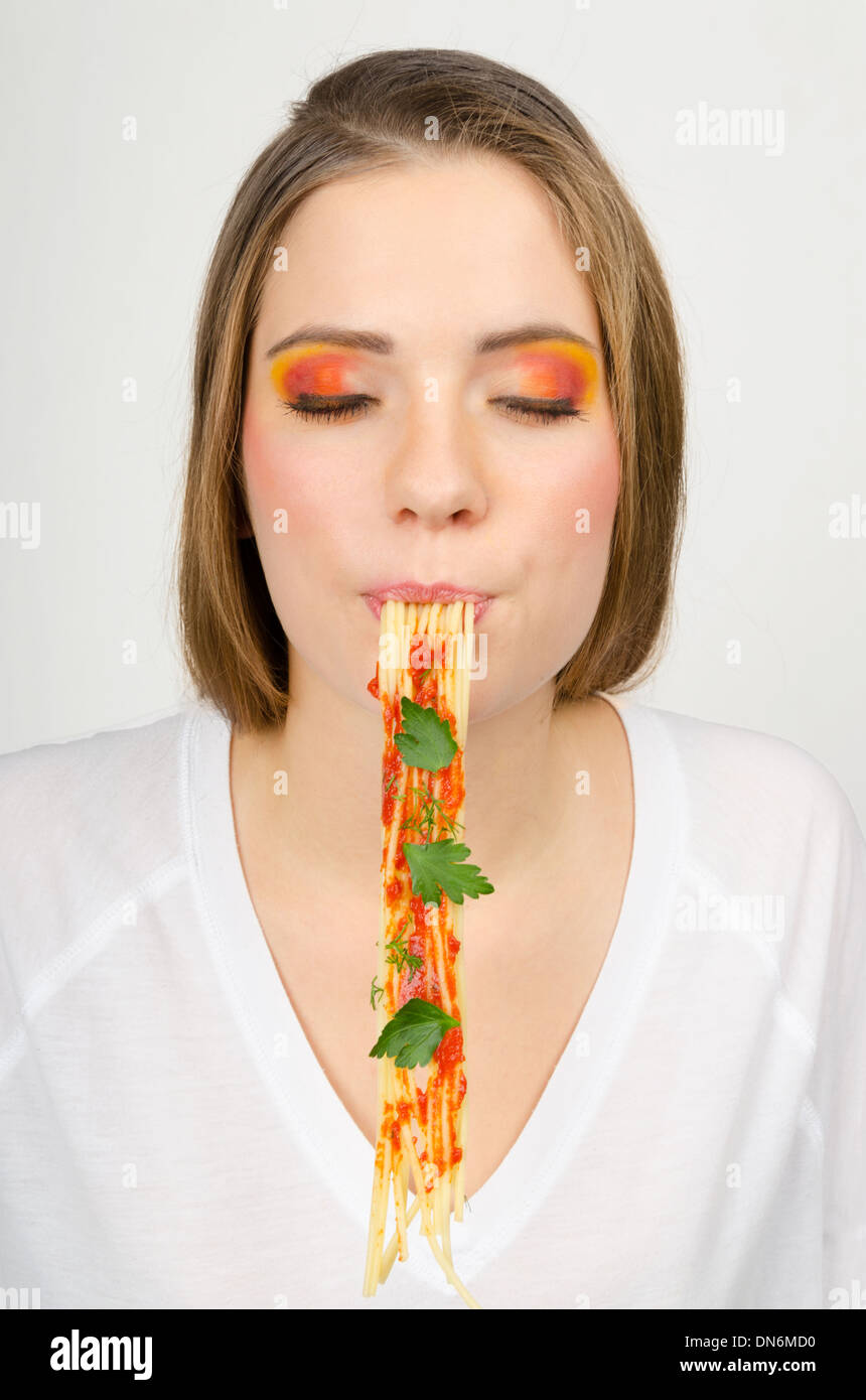Mujer comiendo espaguetis con los ojos cerrados Foto de stock
