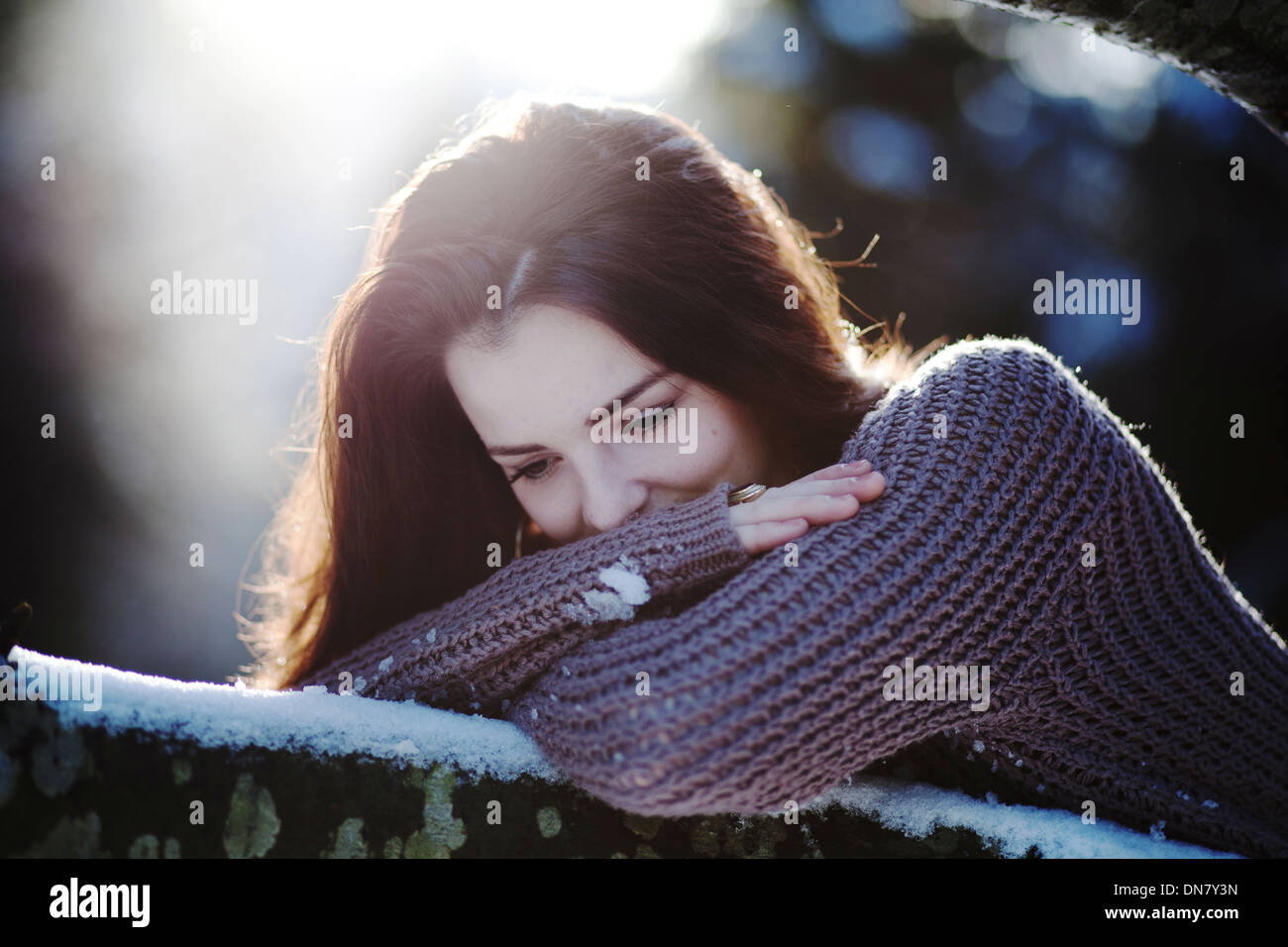Mujer joven recostado sobre el tronco de un árbol en la nieve Foto de stock