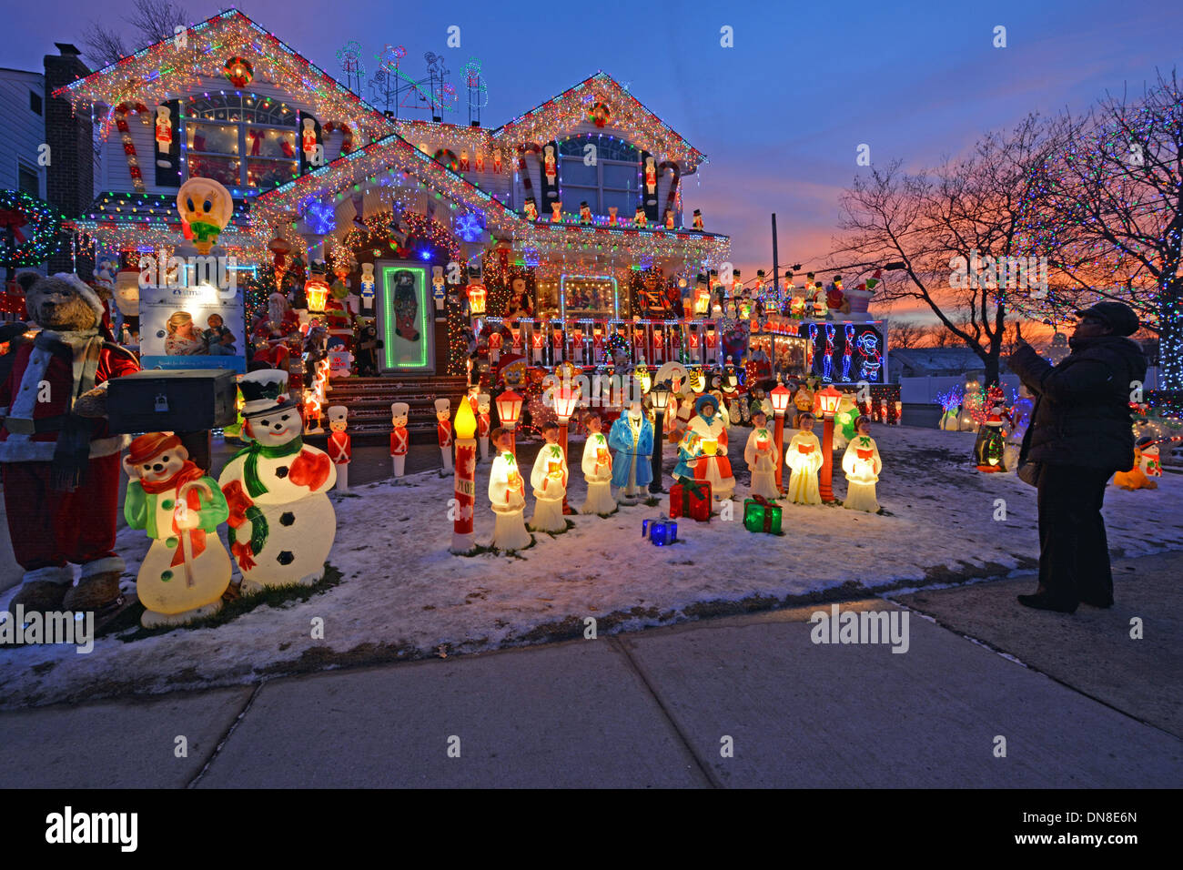 Una mujer toma una foto con un iPad de una casa en Bayside, Queens, Nueva York con una iluminación elaborada para Navidad. Foto de stock