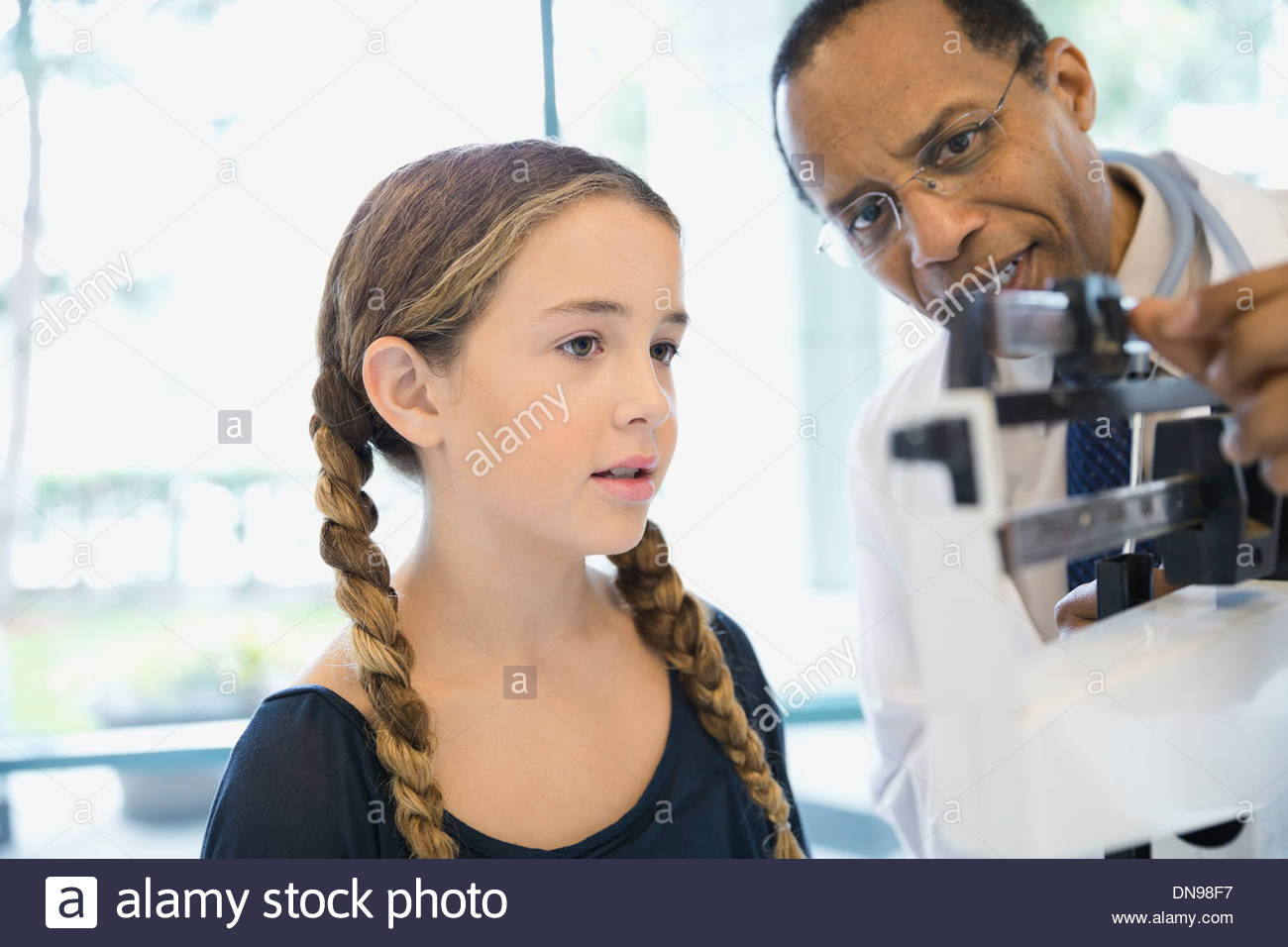 Médico hombre midiendo el peso de niñas Foto de stock