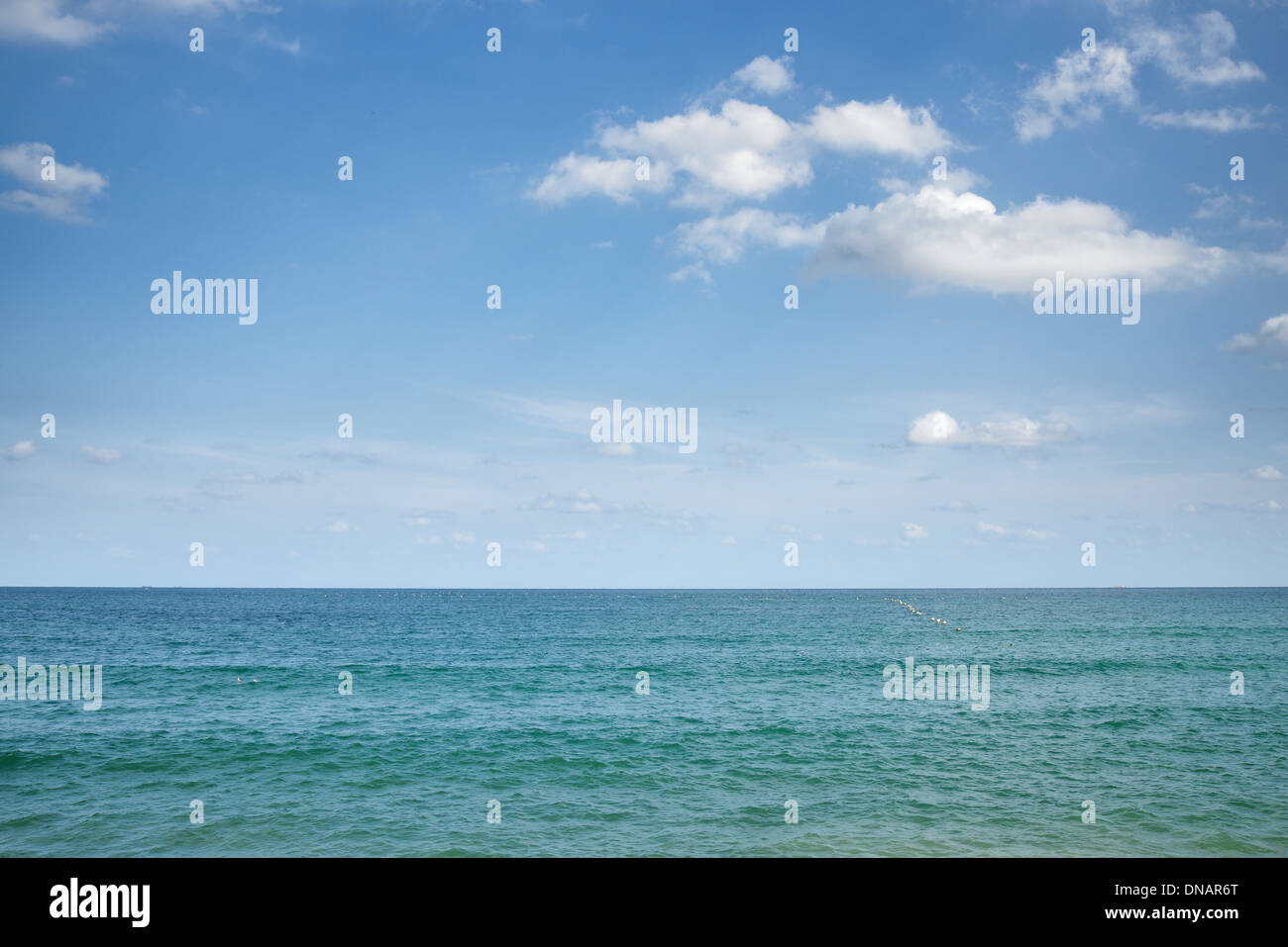 Mar en calma y el cielo azul claro con algunas nubes Foto de stock