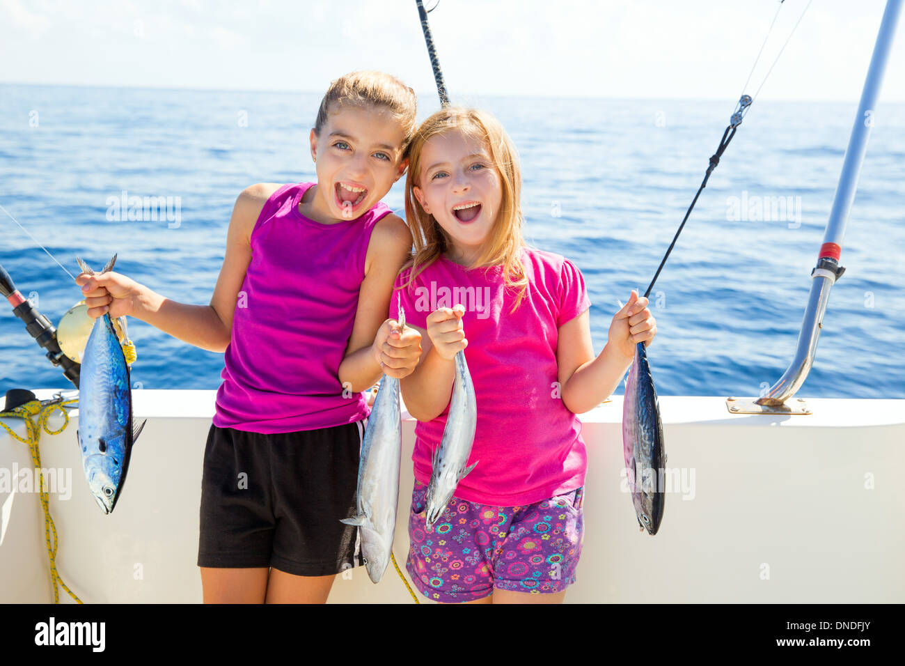 Feliz atún pescadoras kid chicas en barco con peces curricán capturas Foto de stock