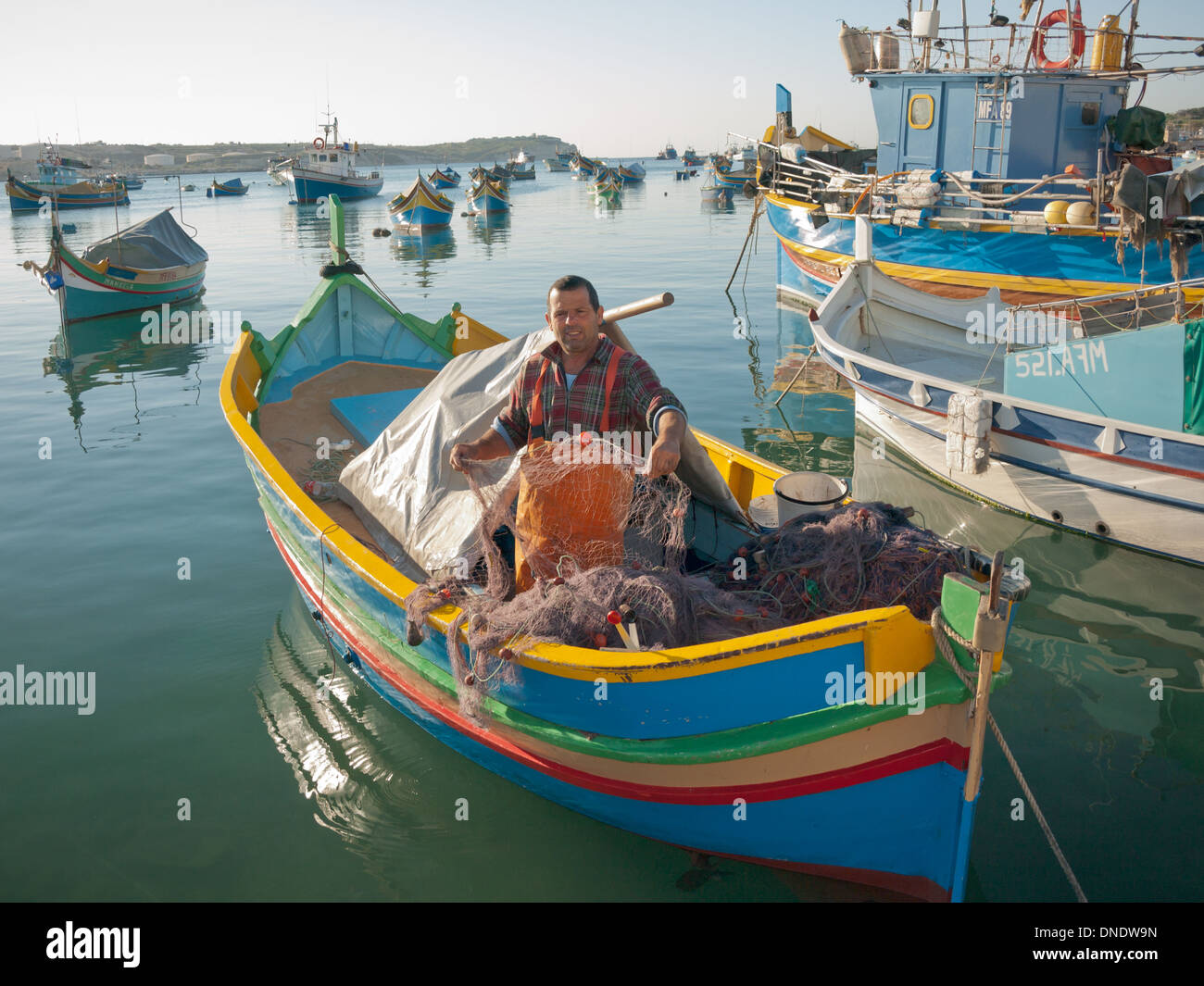 Un pescador maltés local en un luzzu en Puerto de Marsaxlokk, Malta. Foto de stock