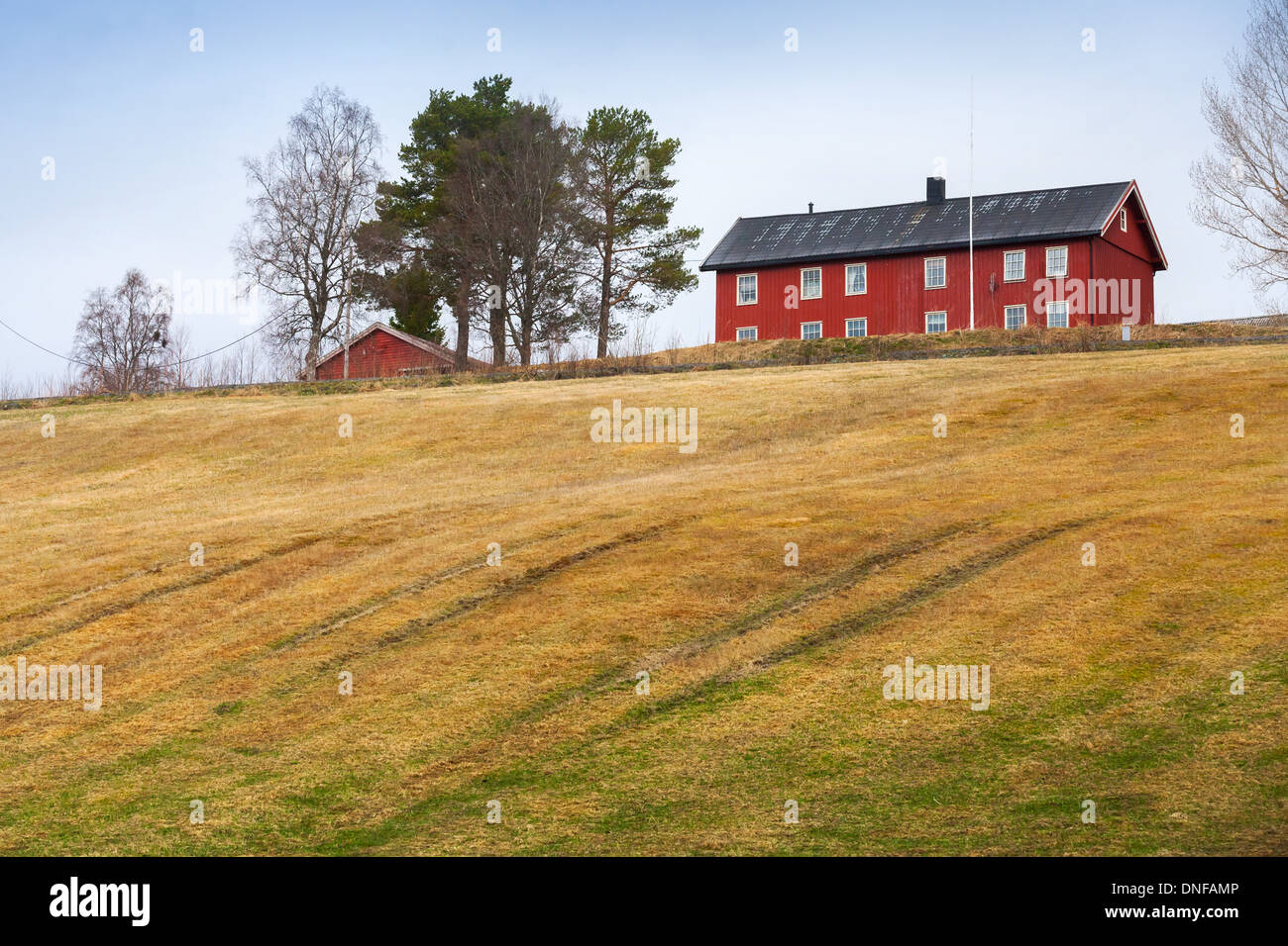 Rural de primavera el paisaje noruego con casa y campo rojo Foto de stock