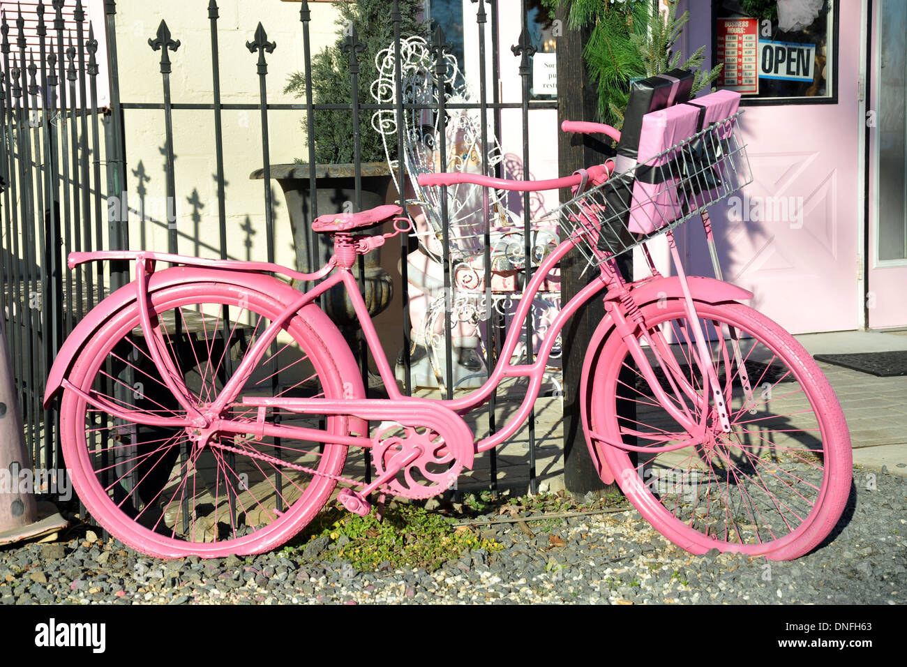 Las niñas rosa bicicleta estacionada en la verja de hierro negro con el regalo en la cesta Foto de stock