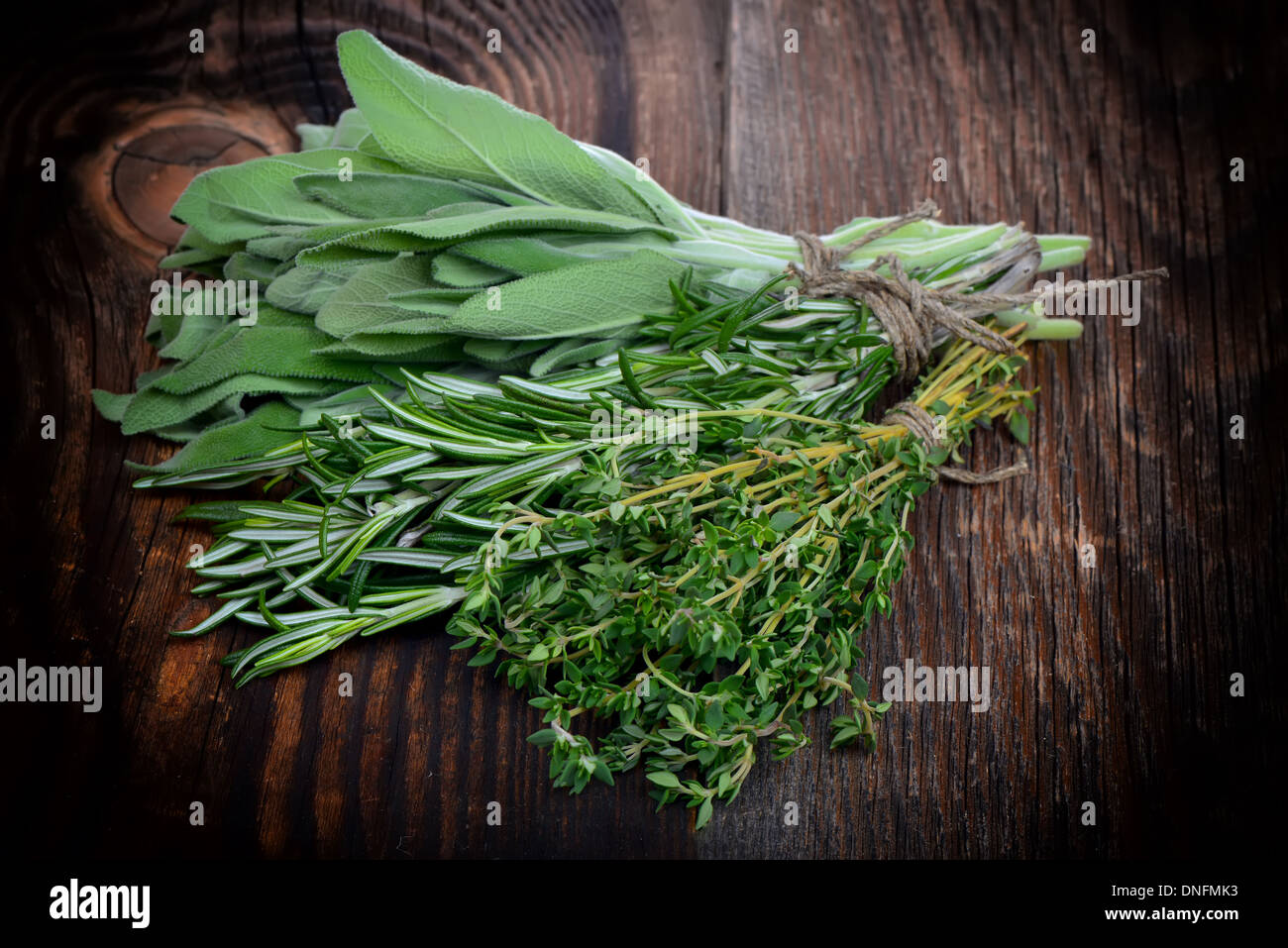 El tomillo, el romero fresco y hojas de laurel enlazado a una tabla de