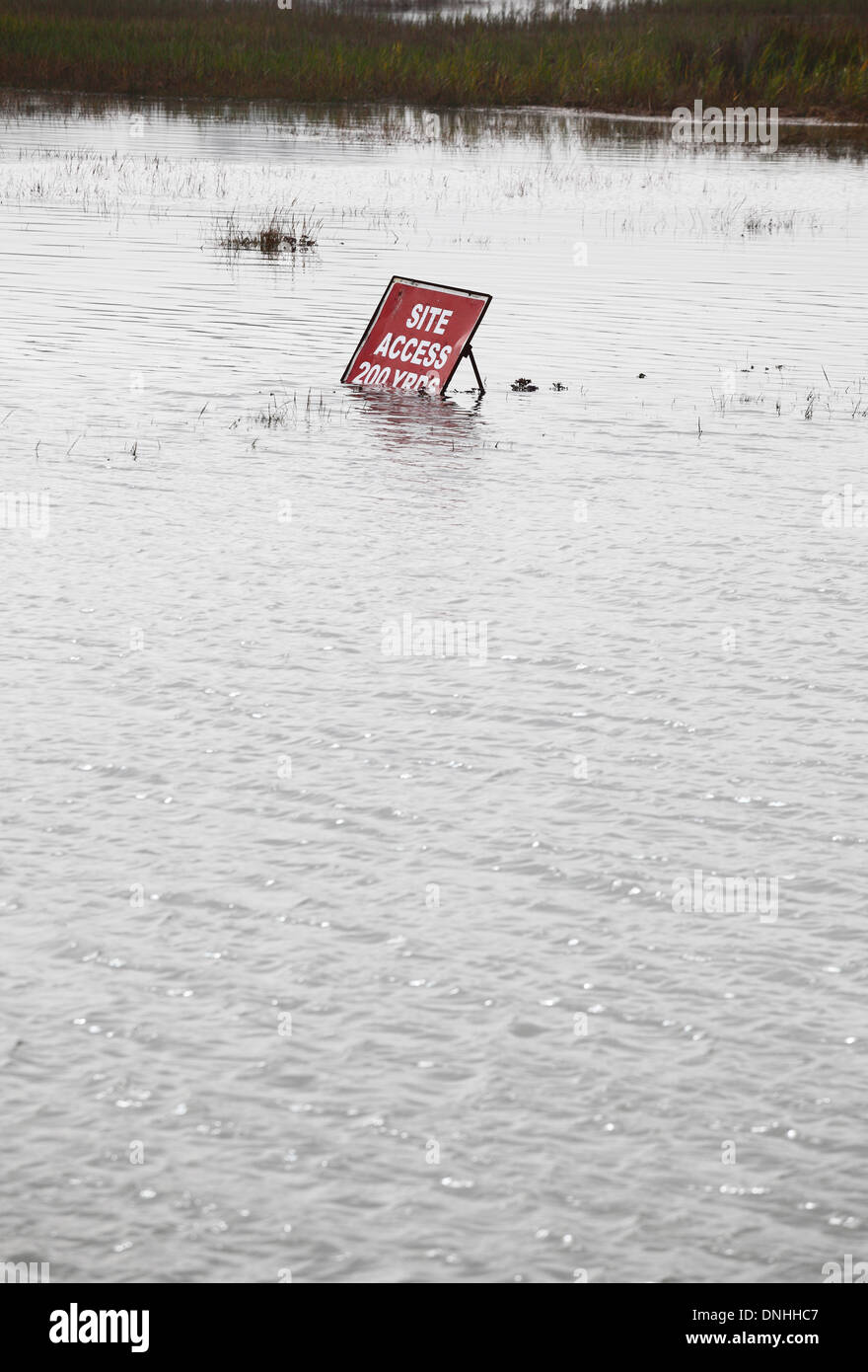 'Precaución' entrada del sitio firmar junto a un mal camino inundado. Foto de stock