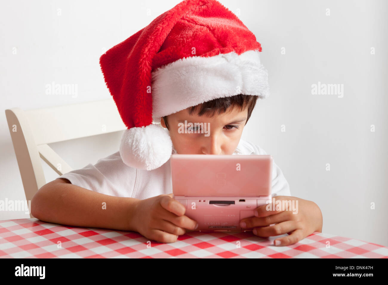 Chico en Santa's hat juega en Nintendo DS Foto de stock