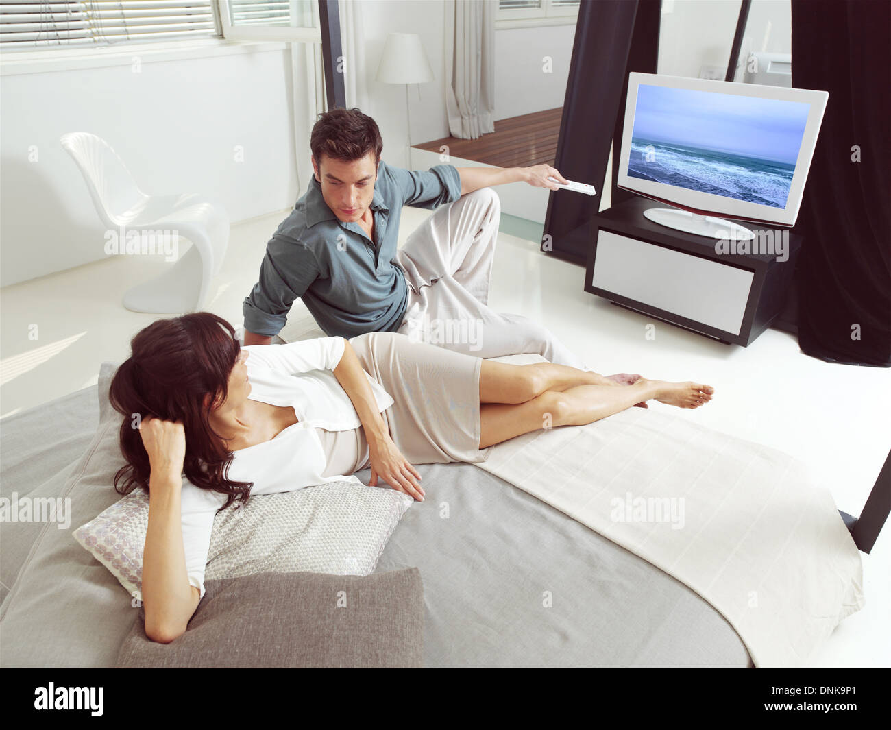 Retrato de la feliz pareja sentada en un sofá y viendo la televisión juntos Foto de stock