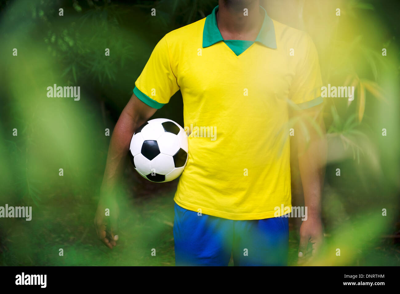 Jugador de fútbol brasileño en Brasil colores uniformes en bambú selva  tropical permanente sosteniendo un balón de fútbol Fotografía de stock -  Alamy