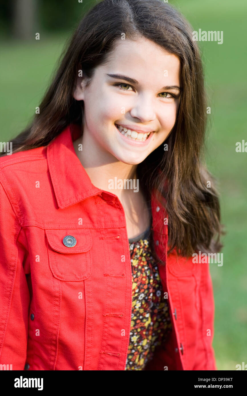 Retrato de pre-teen chica con de largo, pelo castaño, vistiendo chaqueta roja, exteriores Foto de stock