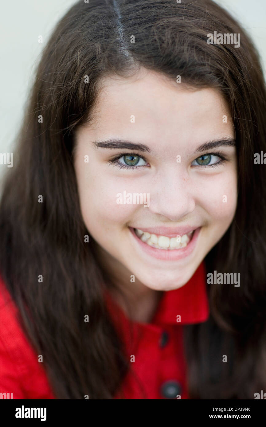 Close-up retrato de pre-teen chica con de largo, pelo castaño, sonriendo y mirando a la cámara Foto de stock