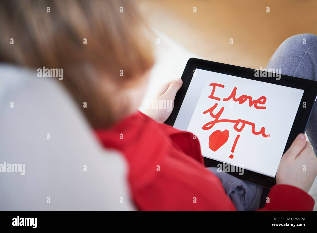 Vista trasera del niño sosteniendo tablet diciendo "I love you" Foto de stock