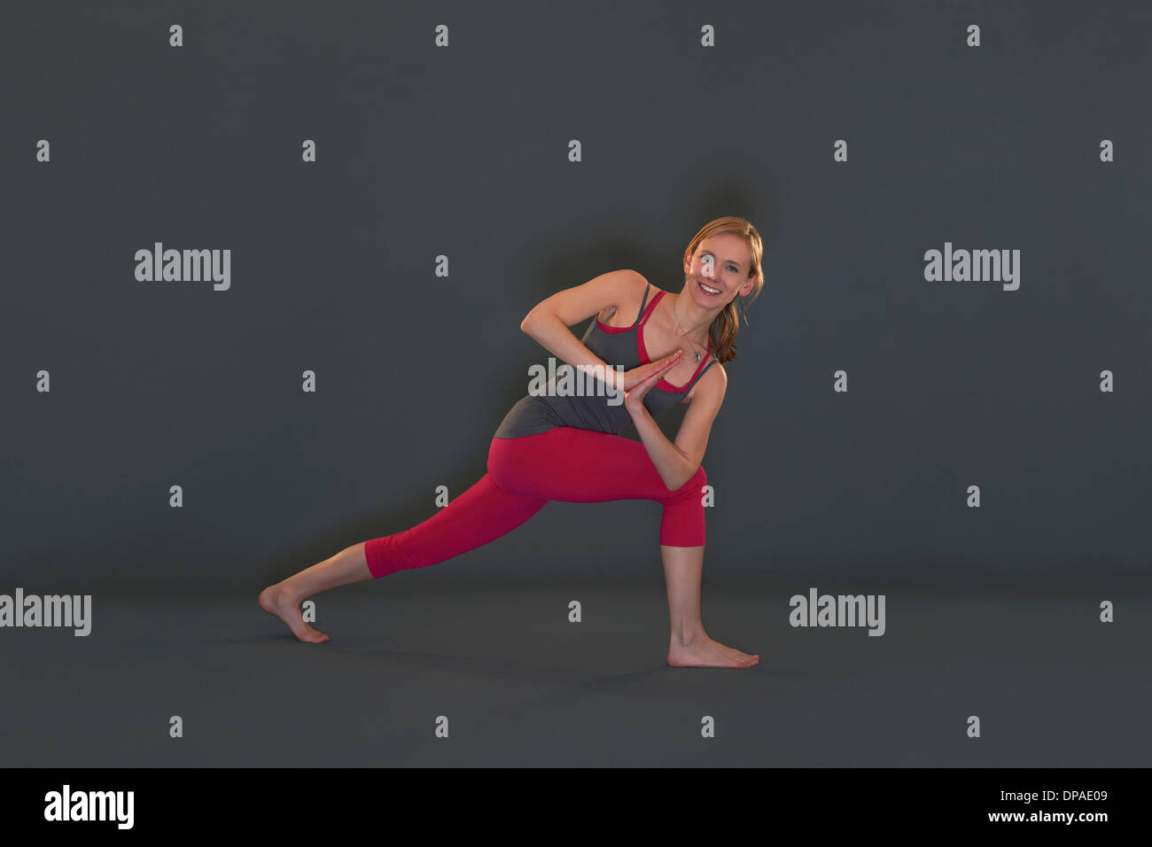 Mujer en pose yoga sobre fondo gris Foto de stock