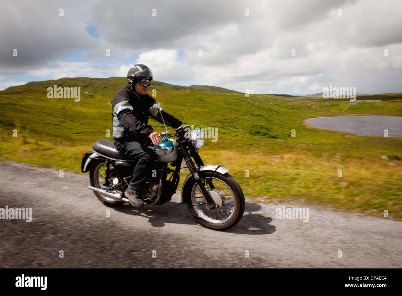 Senior masculino en moto en carretera rural Foto de stock