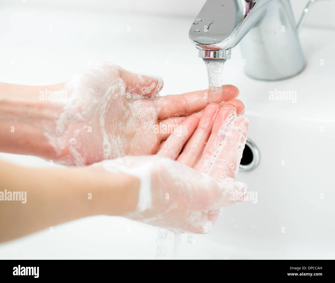 Lavado de manos femeninas con jabón en el baño cerrar Foto de stock