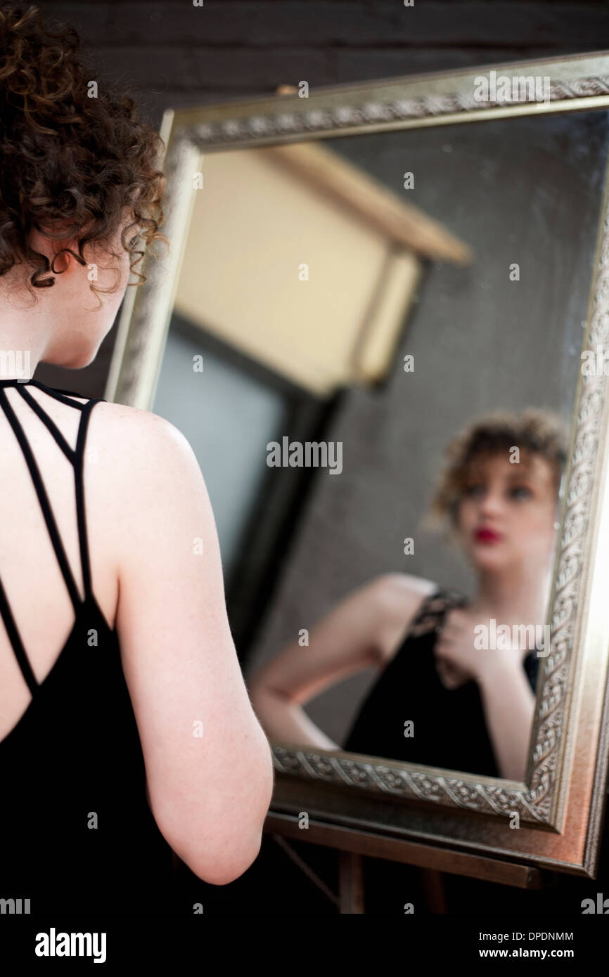 Mujer joven mirando la reflexión en espejo Foto de stock
