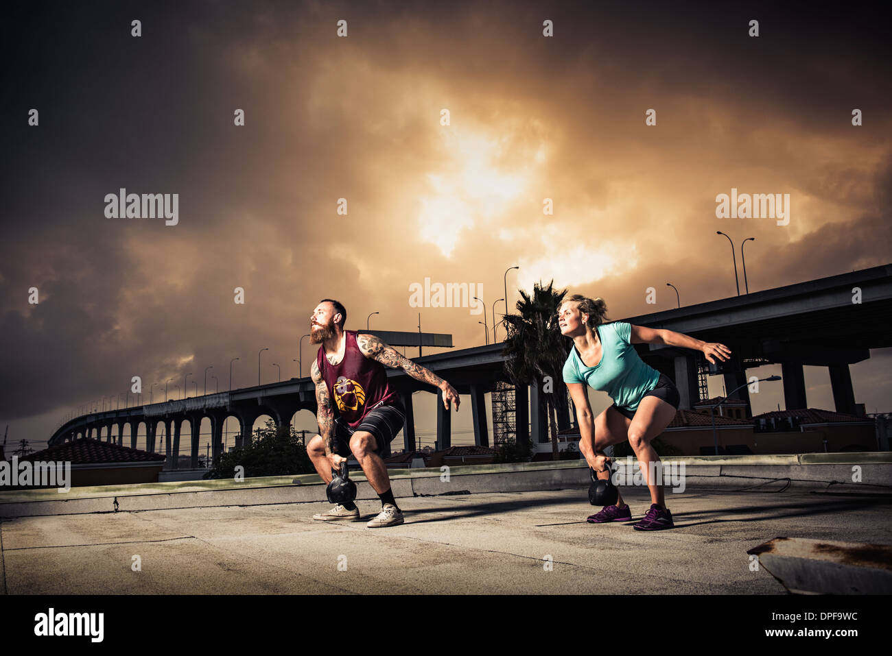 El hombre y la mujer con entrenamiento en el gimnasio de la azotea kettlebells Foto de stock