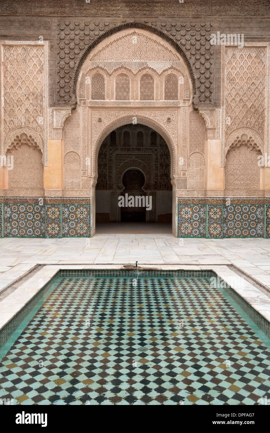 Patio y piscina con puerta ornamental tradicional marroquí en la Medersa Ben Youssef, la UNESCO Sitio, Marrakech, Marruecos Foto de stock