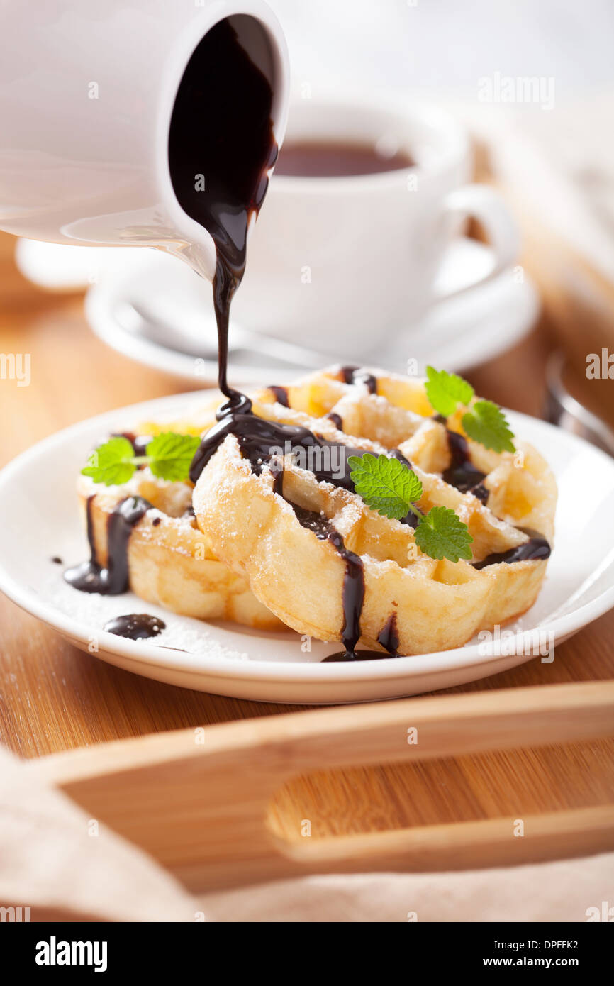 Verter el chocolate sobre waffles belgas para el desayuno Foto de stock