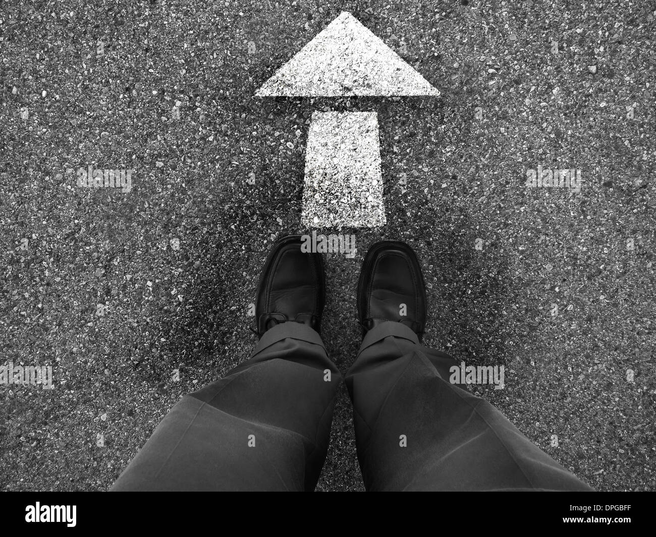 Hombre de negocios de pie en el suelo con una flecha que señala el camino a seguir Foto de stock
