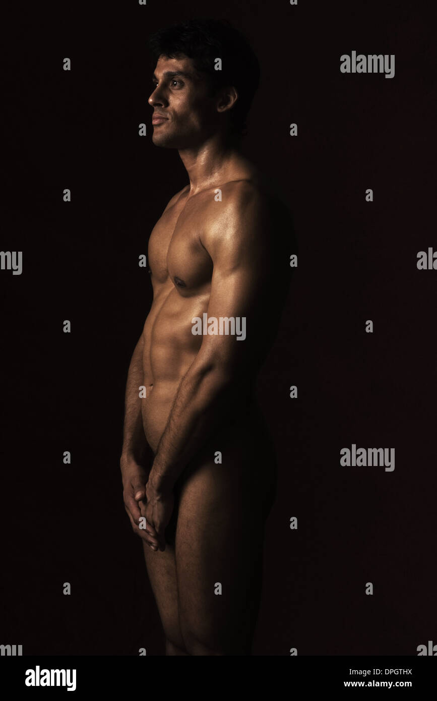 Hombre de pie desnudo en la oscuridad, tres cuartos de longitud Fotografía  de stock - Alamy