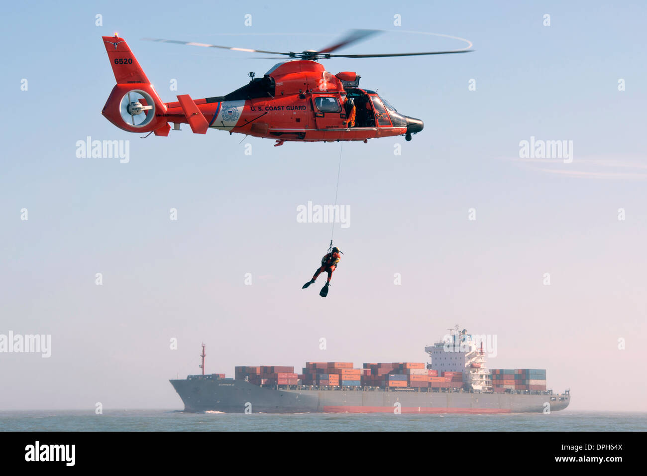 US Coast Guard oficial pequeño de 3ª clase Andrew Wilson, un nadador de rescate con Air Station Houston cuelga encima de la bahía de Galveston durante la capacitación Enero 9, 2014 en Galveston, Texas. Foto de stock