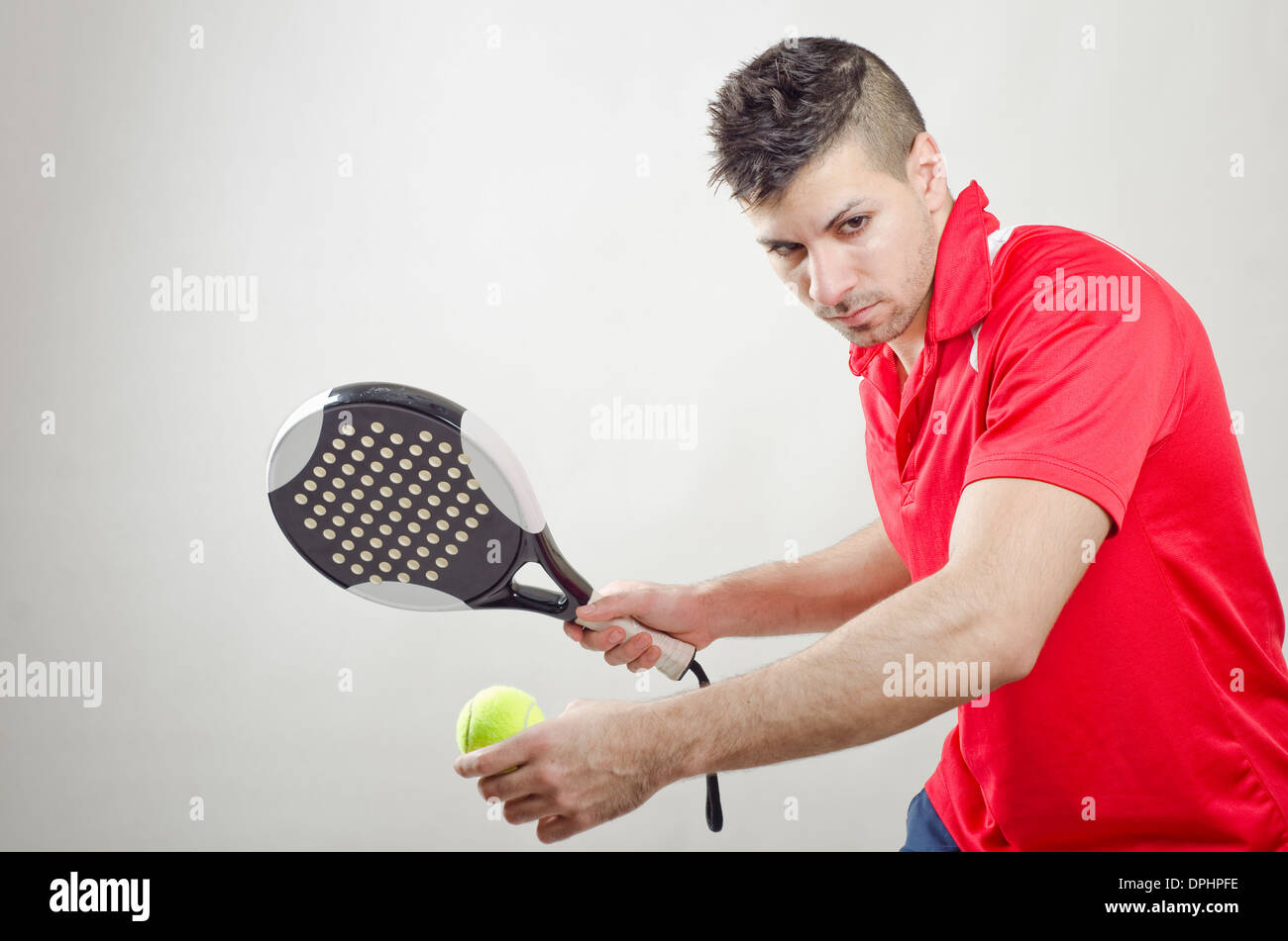 Jugador de tenis paddle listo para servir sobre fondo gris Foto de stock