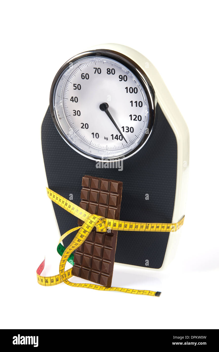 Una escala con cinta métrica y chocolate Foto de stock