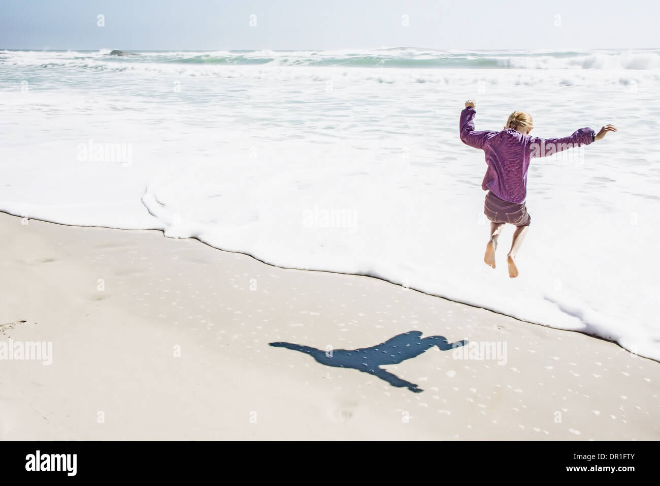 Niña jugando en las olas en sunny beach Foto de stock
