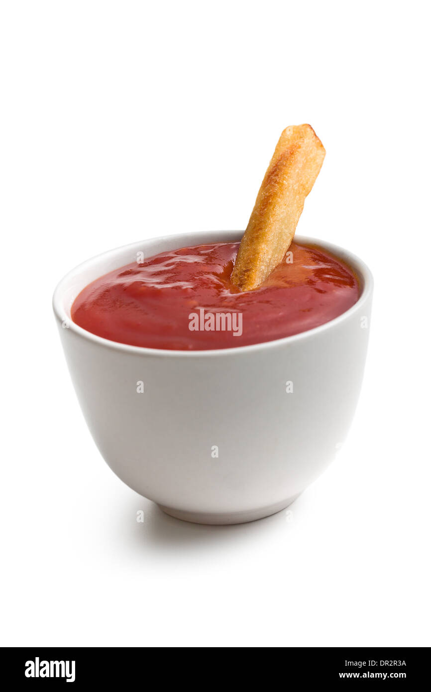En un tazón de ketchup con papas fritas sobre fondo blanco. Foto de stock