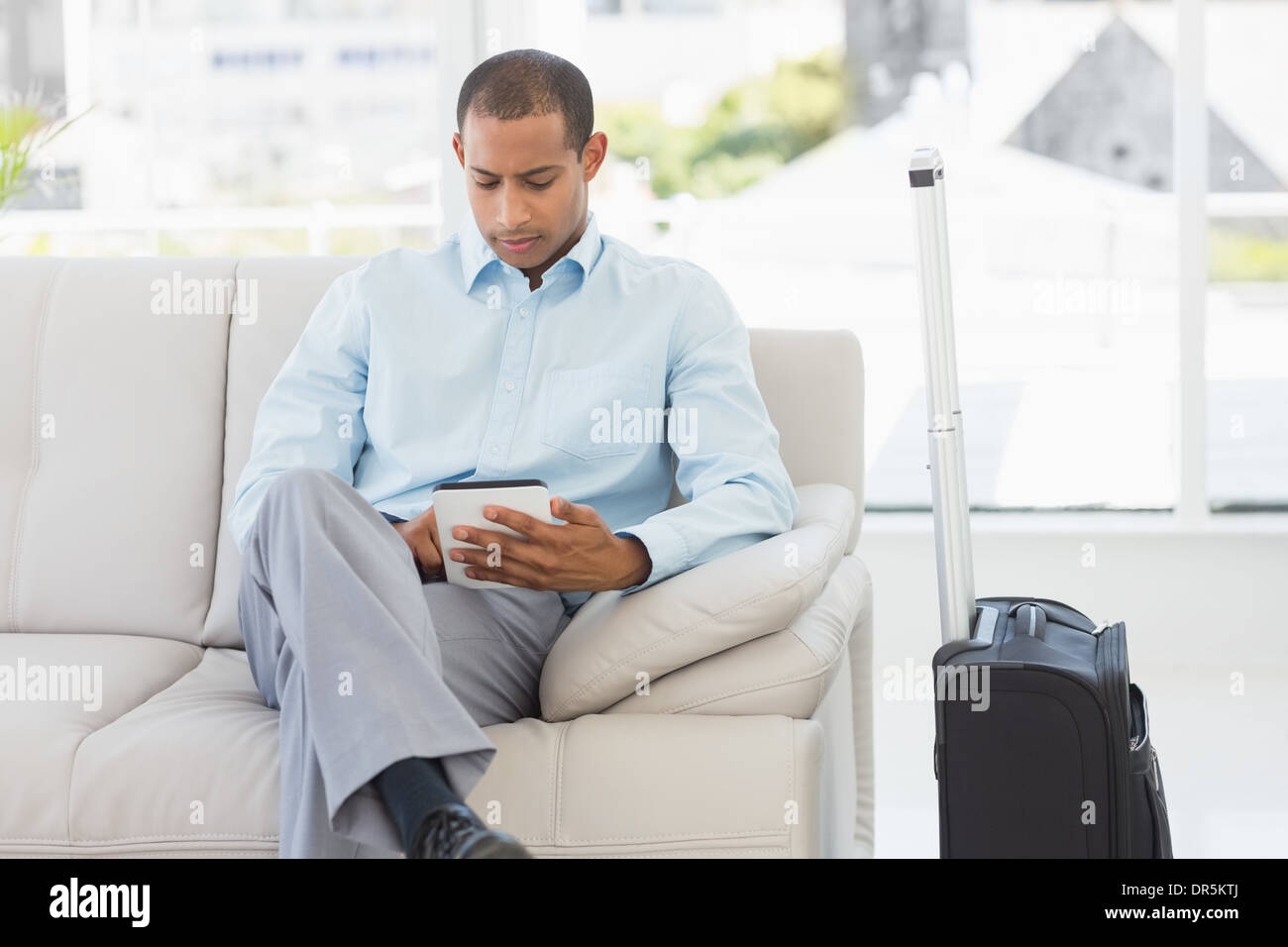 Hombre sentado en el sofá esperando a salir en viaje de negocios Foto de stock