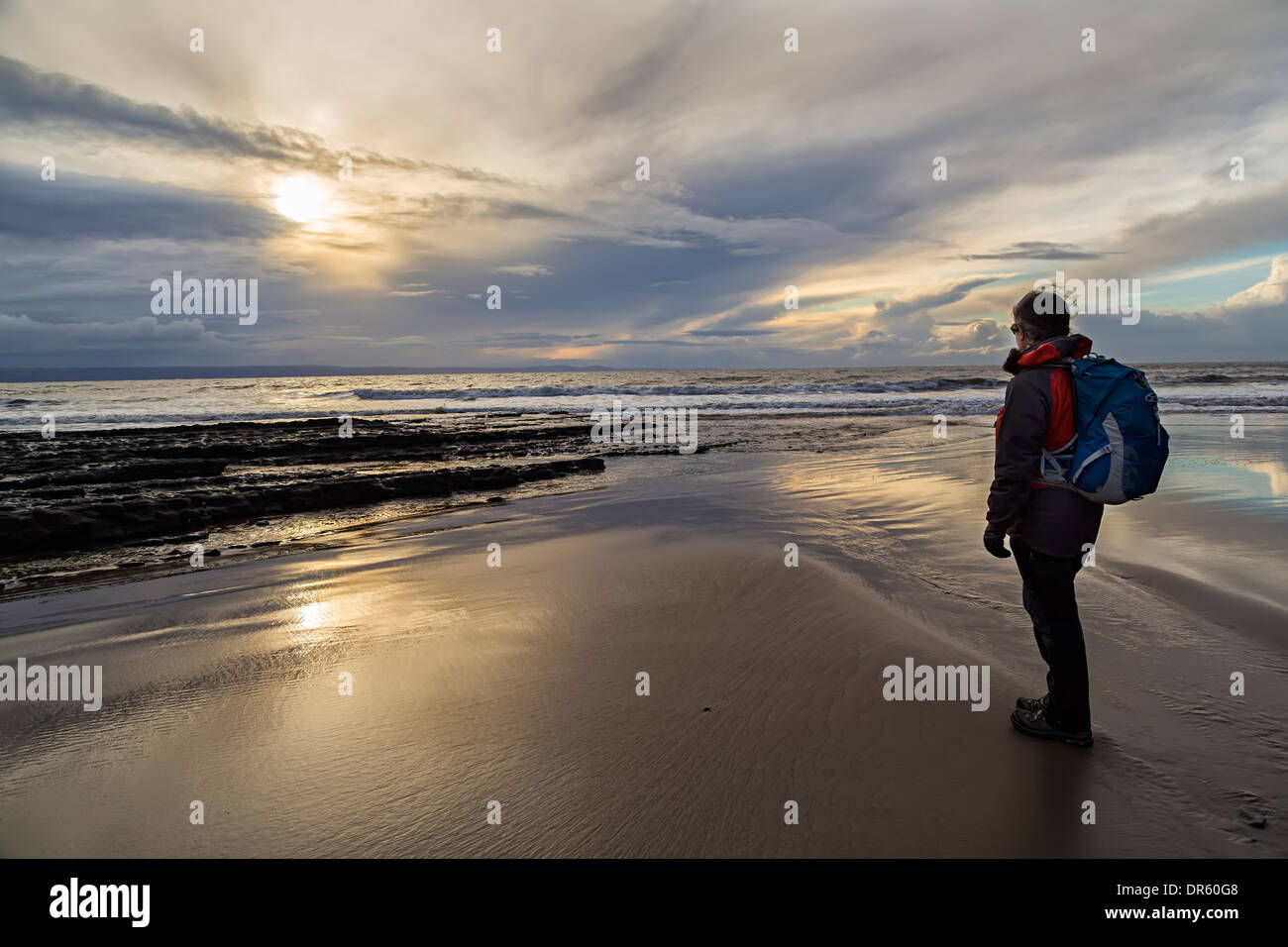 Mujer caminante de pie en la playa, al atardecer, Dunraven, Glamorgan, Wales, REINO UNIDO Foto de stock