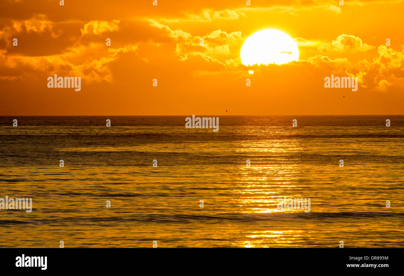 Puesta de sol sobre el mar, en parte, detrás de las nubes. Foto de stock