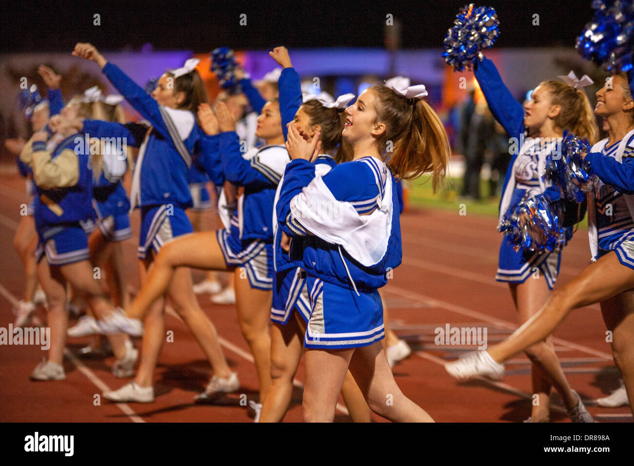Cheerleaders inspirar la multitud en un partido de fútbol nocturno en San Juan Capistrano, CA. Foto de stock