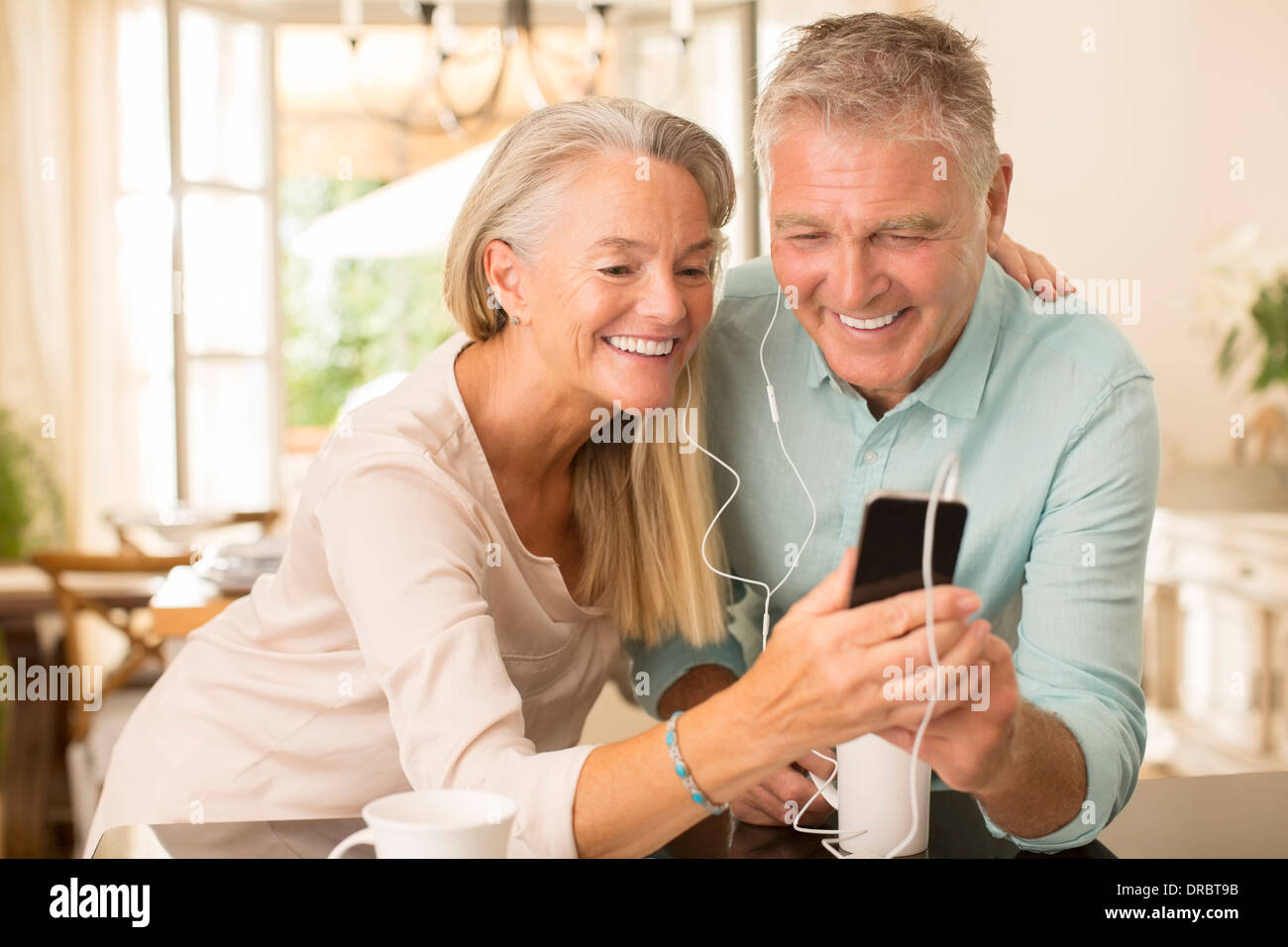 Senior pareja compartiendo un reproductor de mp3 en cocina doméstica Foto de stock