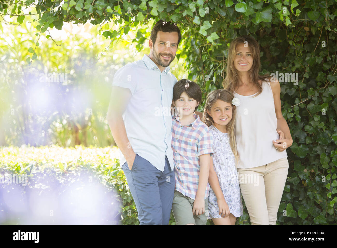 Familia sonríe bajo la hiedra Foto de stock