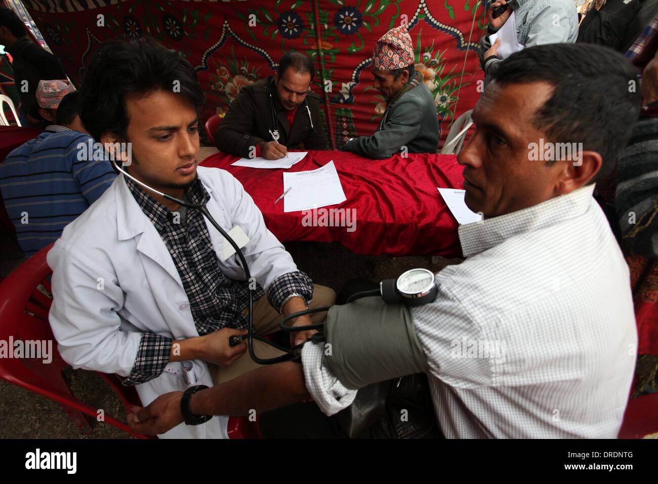 Katmandú, Nepal. 24 ene, 2013. Un médico revisa la presión sanguínea de un paciente en un campamento de salud gratuita organizada por la Asociación Médica de Nepal (NMA) como parte de una protesta en curso en Tundikhel, Katmandú, Nepal, 23 de enero de 2014. La protesta exige al gobierno para que ponga fin a la injerencia política en el sector de la salud y poner fin a la huelga de hambre del Dr. Govinda K.C. Crédito: Sunil Sharma/Xinhua/Alamy Live News Foto de stock