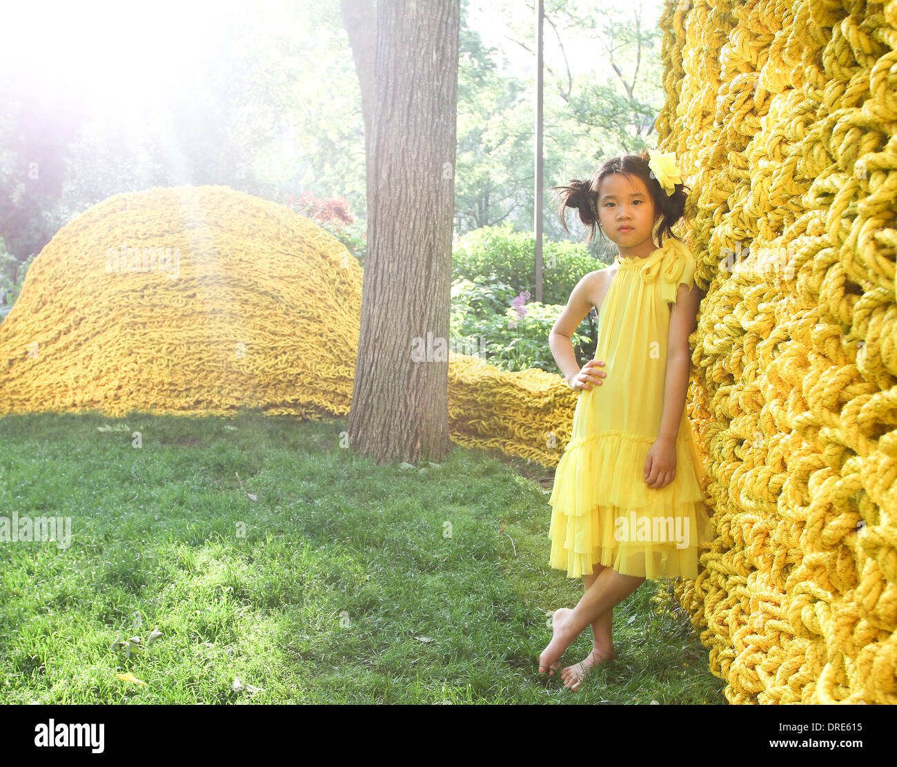 Joven asiática en vestido amarillo cerca de pared amarilla Foto de stock