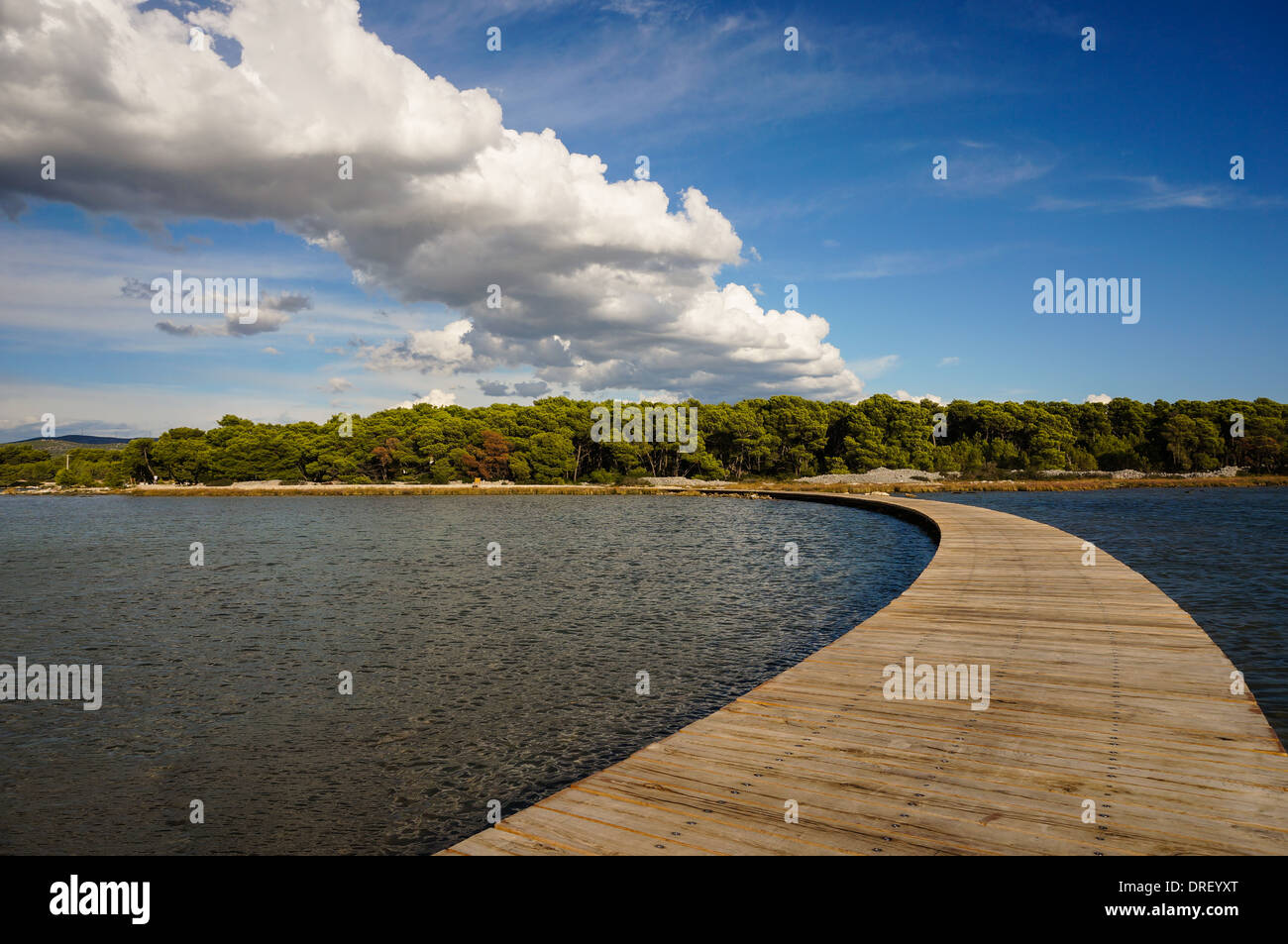 Boardwalk es madera curvada que conecta el continente con una isla de nubes son el reflejo de la forma de este paseo Foto de stock