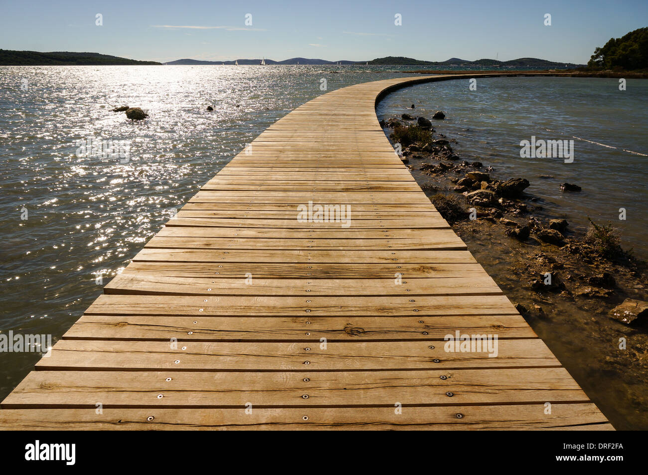 Boardwalk es madera curvada que conecta el continente con una isla Foto de stock