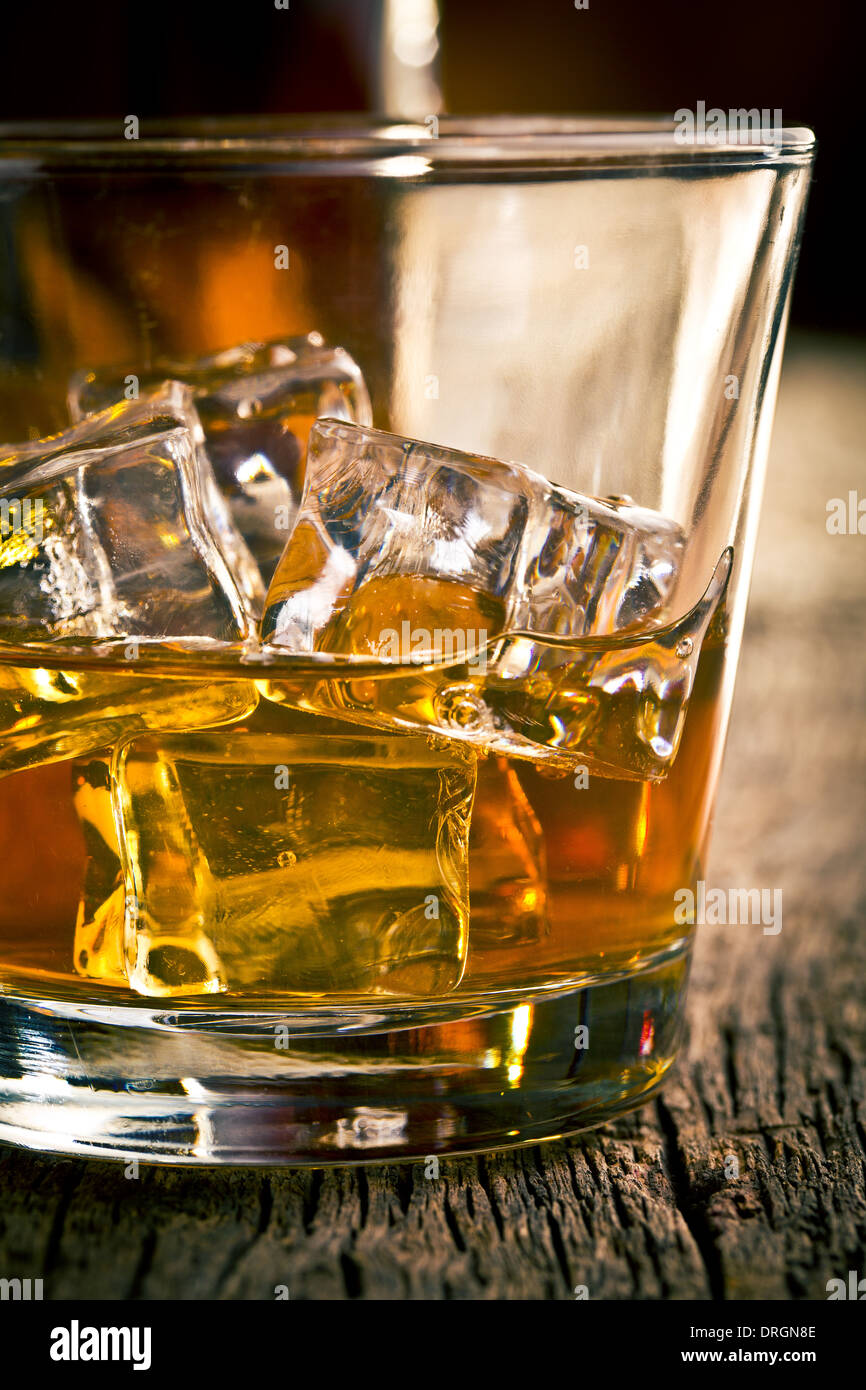 En el vaso de whisky con hielo sobre la mesa de madera Foto de stock