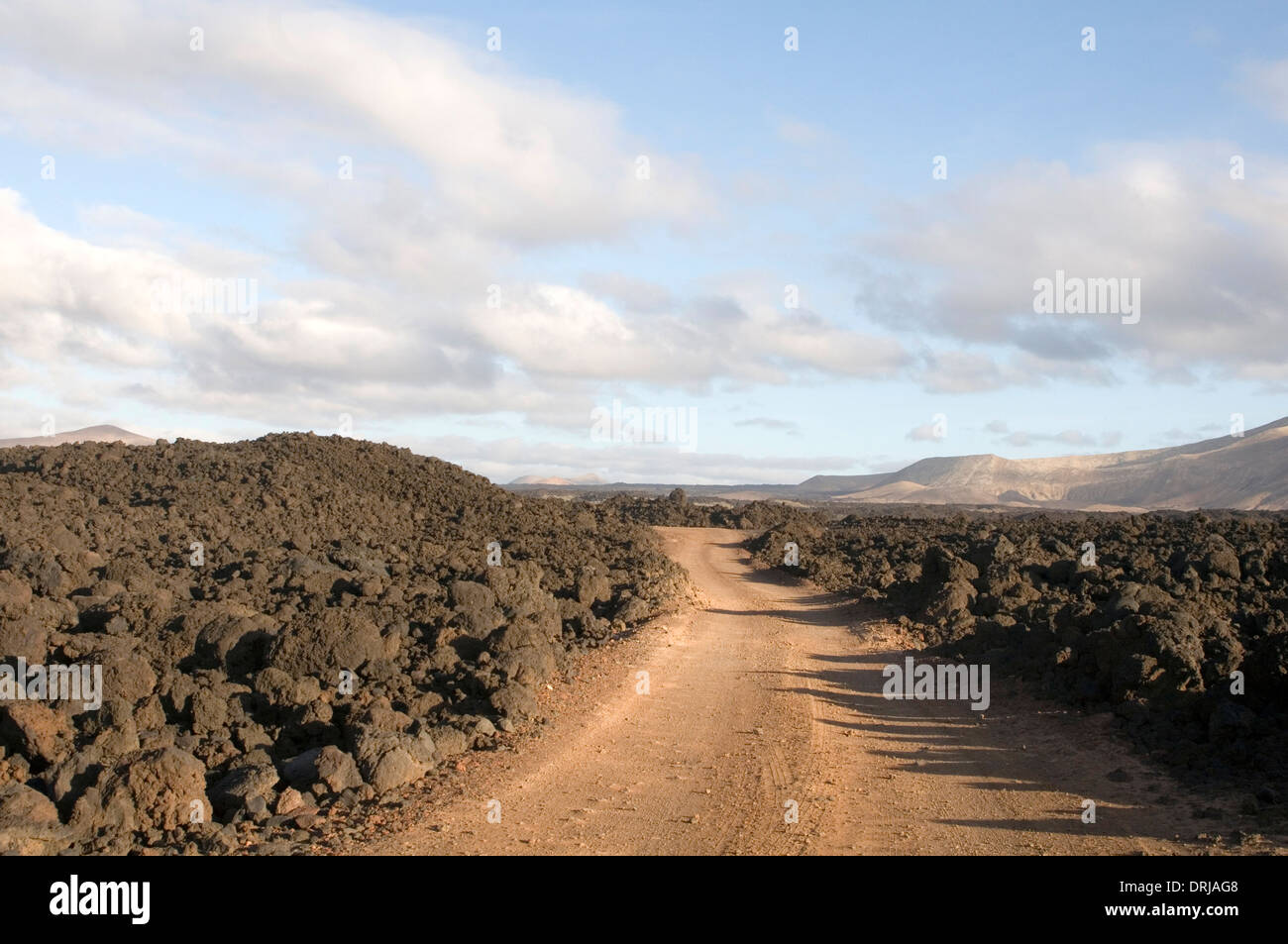 Suelo pedregoso camino de tierra vía carreteras sin asfaltar pistas de polvo áspero a través de Boulder, campo de lava Lanzarote islas canarias Foto de stock