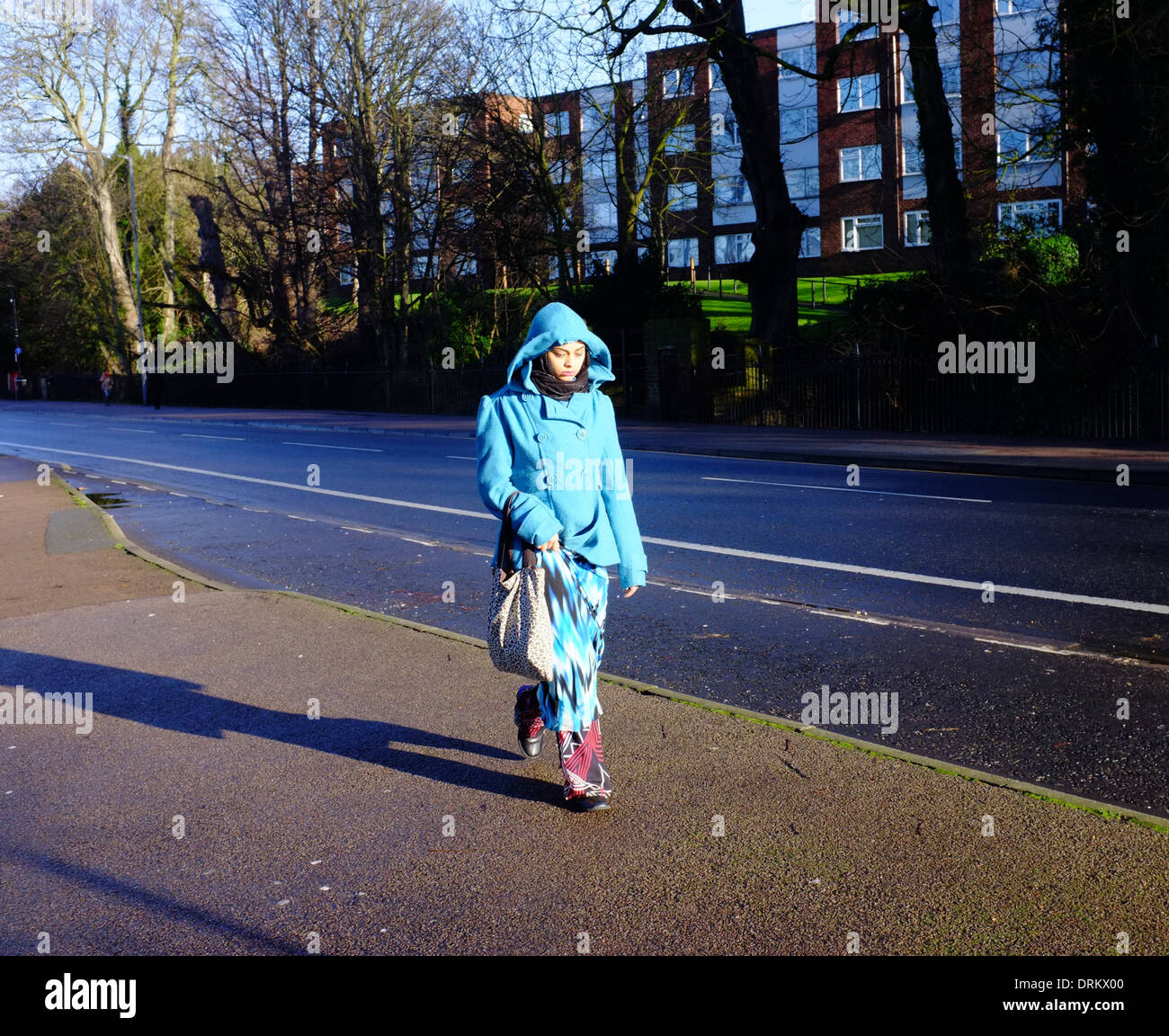 Mujer Asiática en Blue Coat encapuchados caminando en Luton Foto de stock